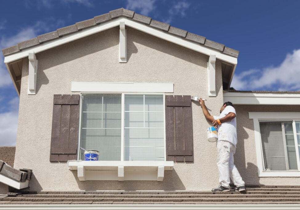 Busy House Painter Painting the Trim And Shutters of A Home.